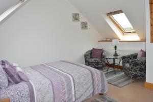 a bedroom with a bed and a window and a chair at Penlan Coastal Cottages in Aberporth