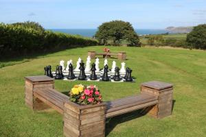 a garden with a chessboard and a bench and flowers at Penlan Coastal Cottages in Aberporth