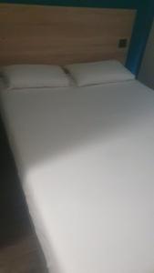 Cama en habitación con 2 almohadas blancas en hotelF1 Marseille Plan de Campagne N°1, en Cabriès