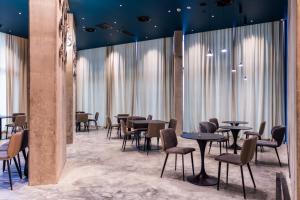 restauracja ze stołami i krzesłami oraz dużymi oknami w obiekcie Nova Concierge Hotel w mieście Batumi