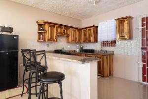 a kitchen with wooden cabinets and bar stools at Fully AC 2BR, 5 mins from Ian Fleming Int Airport in Boscobel