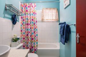 ein Badezimmer mit einem farbenfrohen Duschvorhang und einer Badewanne in der Unterkunft Fully AC 2BR, 5 mins from Ian Fleming Int Airport in Boscobel