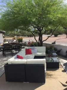 a white couch with two red pillows sitting under a tree at Luxurious 4-bedroom home in Scottsdale in Scottsdale