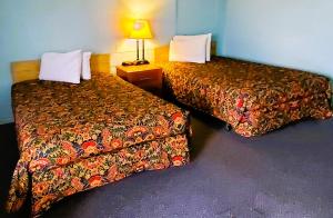 una habitación de hotel con 2 camas y una lámpara en Holiday Host Motel & RV Park, en Sonora