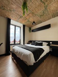 a bedroom with a large bed with a wooden ceiling at Hôtel de la Gare Sévérac in Sévérac-le-Château