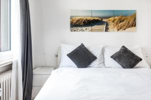 a bedroom with a white bed with black pillows at Cooldis G in Kreuzlingen