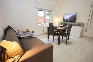 een woonkamer met een bank en een tafel met stoelen bij Appartamento Moderno per 6 Aviano A/C Parking in Aviano