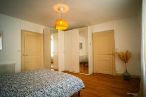 a bedroom with a bed and a mirror and a lamp at La Jeannette - séjour premium tout inclus dans une maison proche gare-centre avec lit 160 Emma, terrasse, parking et plus in Châteauroux