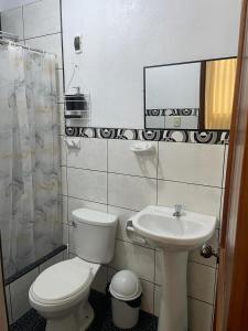 La salle de bains est pourvue de toilettes et d'un lavabo. dans l'établissement Hospedaje Familiar Laos, à Oxapampa