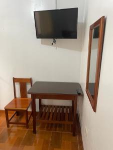 a table with a chair and a television on a wall at Hospedaje Familiar Laos in Oxapampa