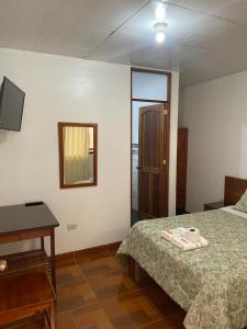 - une chambre avec un lit, une table et un miroir dans l'établissement Hospedaje Familiar Laos, à Oxapampa