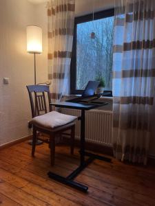 a desk with a laptop and a chair in front of a window at Ferienwohnung am Waldrand 