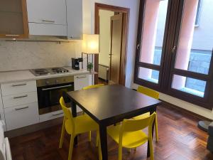 a kitchen with a table and yellow chairs at City Center - 50 metri dal Centro Storico in Cremona