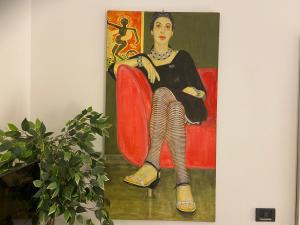 une peinture d'une femme assise sur une chaise rouge dans l'établissement City Center - 50 metri dal Centro Storico, à Crémone