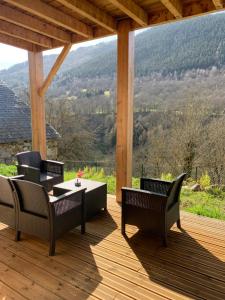 un patio con sillas y una mesa en una terraza de madera. en CHALET en RDJ en VALLEE de LUCHON, en Castillon-de-Larboust