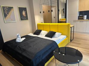 una camera da letto con un letto con testiera gialla e un tavolo di Tauron Arena Apartment with Garage - Kraków Lema a Cracovia