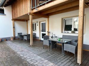 eine Terrasse mit Tischen und Stühlen auf einer Holzterrasse in der Unterkunft Pension Schramm in Karlsruhe