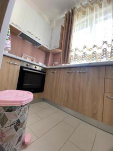 a kitchen with wooden cabinets and a pink stool at Your beach house holidays with all utilities in Shëngjin