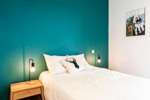 a bedroom with a white bed with a blue wall at Les Terrasses du Noirmont 1 in Les Rousses
