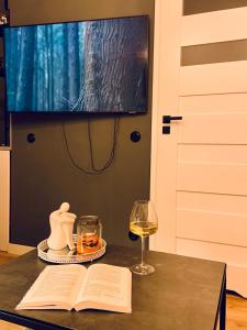 a table with a book and a glass of wine at Garden Place Apartment in Warsaw