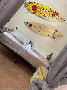 una tabla de surf colgada en una pared junto a una cama en Tommy House 19 en Focene