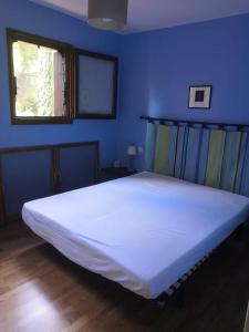 a large white bed in a blue room with a window at Collioure, entre mer, piscine & montagne in Collioure
