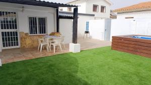 a patio with green grass and a table and chairs at Chalet Bosque10 Piscina Privada entre la playa in Málaga