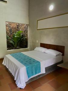 a bedroom with a white bed with a plant at EcoHotel Inka Minka in Santa Marta