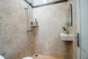 a bathroom with a shower and a toilet and a sink at The Cozy Haven Sanur in Sanur