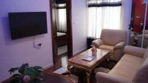 sala de estar con sofá, mesa y TV en Matcheu palace Hôtel, en Yaoundé