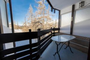 a balcony with a table and a view of snow covered trees at Doux Crépuscule - Départ Randonnée & VTT - Parking in Enchastrayes