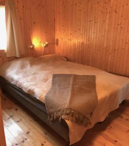Una cama en una habitación de madera con una manta. en Nusfjord Waterfront Rorbu 18, en Ramberg