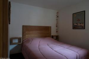 - une chambre avec un lit rose et une tête de lit en bois dans l'établissement Apparts au Cœur de St-Lary - Piscine Chauffée et Sauna, à Saint-Lary-Soulan