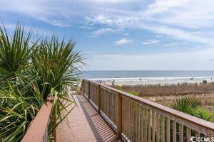 einen Holzsteg zum Strand mit Leuten am Strand in der Unterkunft Camelot By The Sea - Blue C in Myrtle Beach