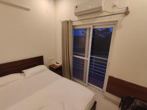 a bedroom with a bed and a large window at MITRA HOTELS in Mysore