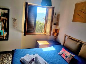 een slaapkamer met een blauw bed en een raam bij Casa kundra vista mare in Scarlino