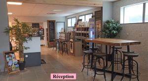 a restaurant with a table and stools in a room at Hôtel Le Clos Badan in Nuits-Saint-Georges