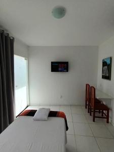 a bedroom with a bed and a television on the wall at Pousada Bsm in Barra de São Miguel