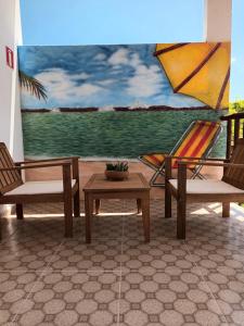 a painting of a patio with two chairs and a table at Pousada Bsm in Barra de São Miguel
