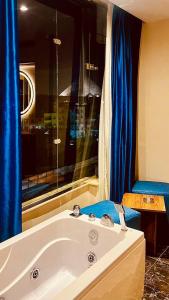 a bathroom with a tub and a window with blue curtains at Pharaonic Pyramids Inn in Cairo
