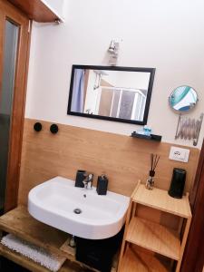 een badkamer met een witte wastafel en een spiegel bij Casa kundra vista mare in Scarlino