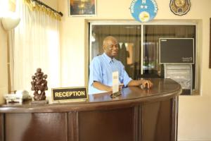 a man is standing at a reception desk at Le Baobab in Bamako