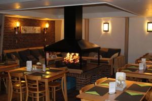 a restaurant with a fireplace and tables and chairs at La cabane, Durbuy in Durbuy