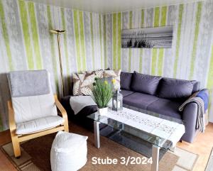sala de estar con sofá púrpura y mesa de cristal en Bungalow Thiele, en Döbeln
