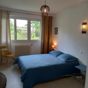 um quarto com uma cama azul e uma janela em La Gisière, Chambres d'hôtes em Challans