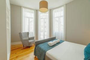 Schlafzimmer mit einem Bett, einem Stuhl und Fenstern in der Unterkunft Bonfim Premium by Hosty in Porto