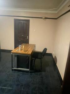 a wooden table and a chair in a room at PiperZ in Entebbe