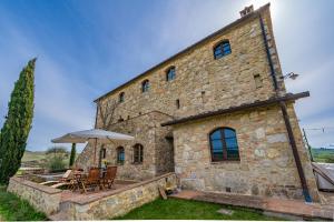 an external view of a stone building with a table and chairs at Il Cipresso del Fossaccio in Asciano