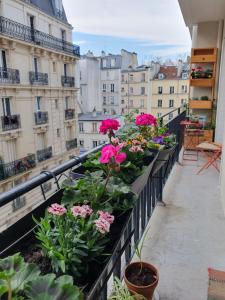 a balcony with pink flowers and buildings at Beautiful 100 m² in the Heart of Paris in Paris