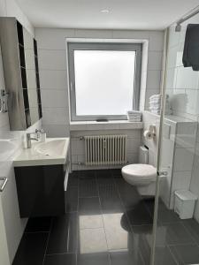 a bathroom with a toilet and a sink and a window at Tondose Apartment in Dortmund